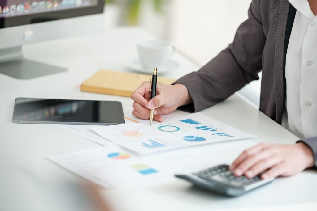 Close up young man with calculator counting making notes at home, hand is writing in a notebook. Savings finances concept. High quality photo