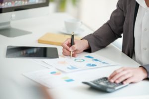 Close up young man with calculator counting making notes at home, hand is writing in a notebook. Savings finances concept. High quality photo