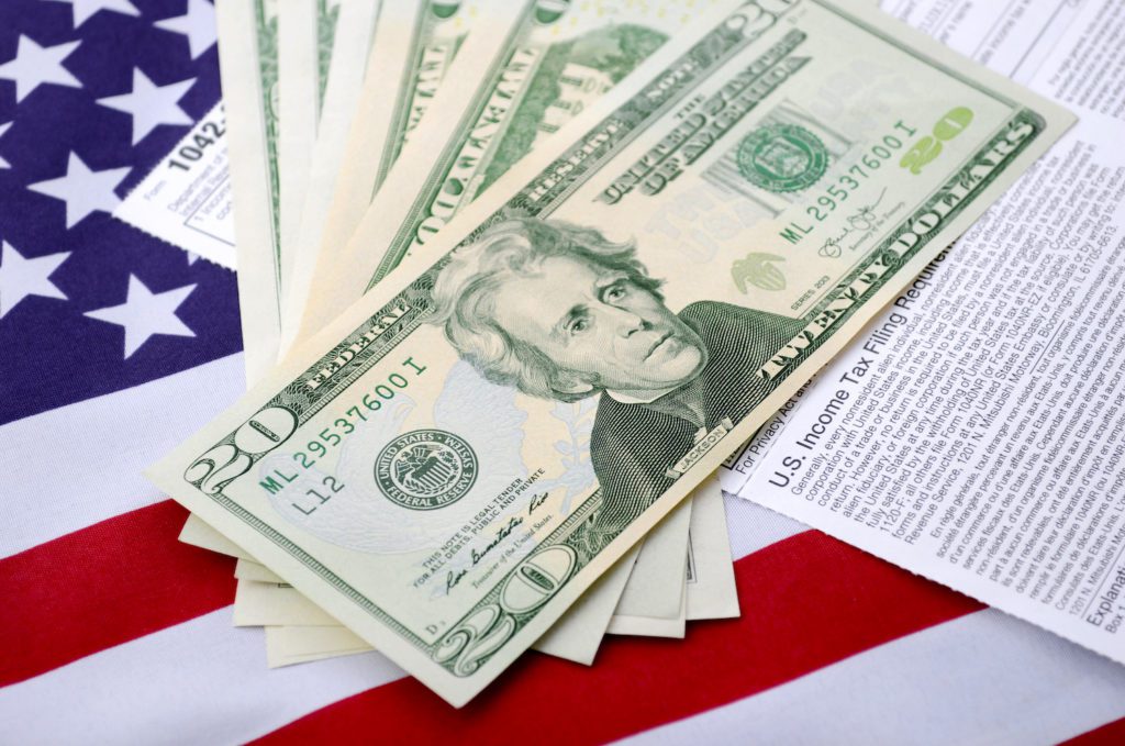 USA Tax Day concept with income tax form and cash on stars and stripes flag