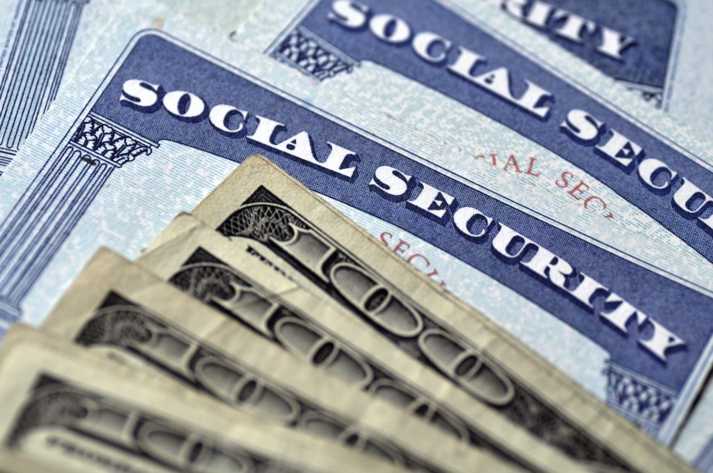 Detail of several Social Security Cards and cash money symbolizing retirement pensions financial safety