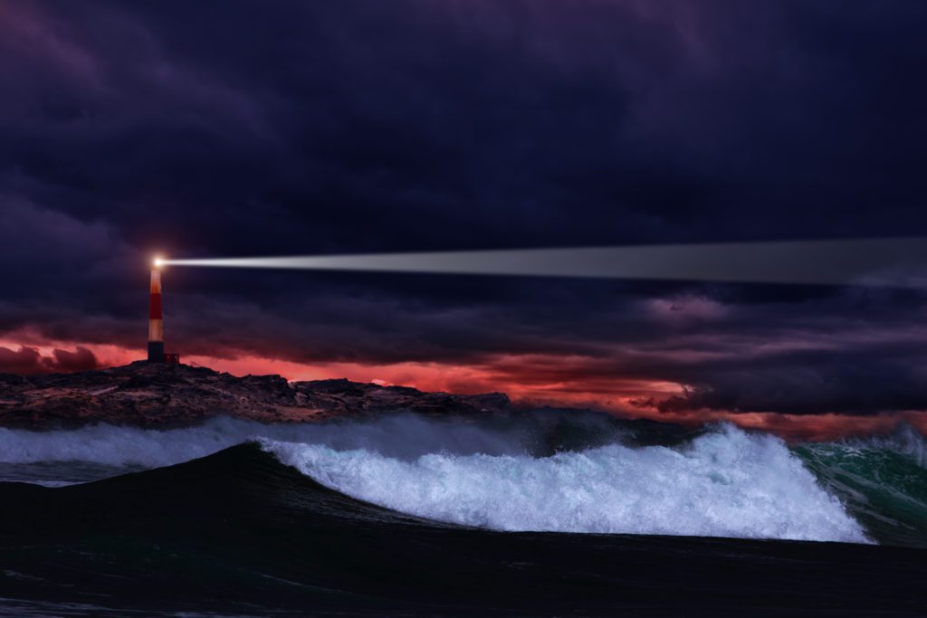 Lighthouse on the rocks in storm ocean
