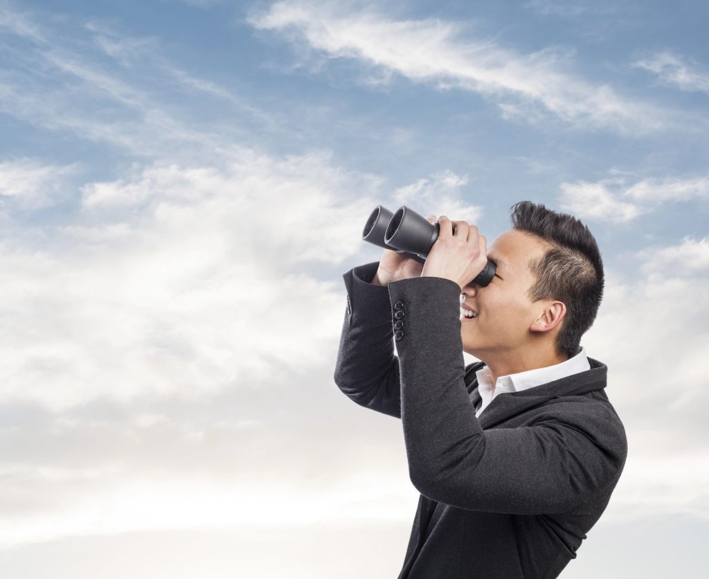 handsome young asian man looking trough a binoculars