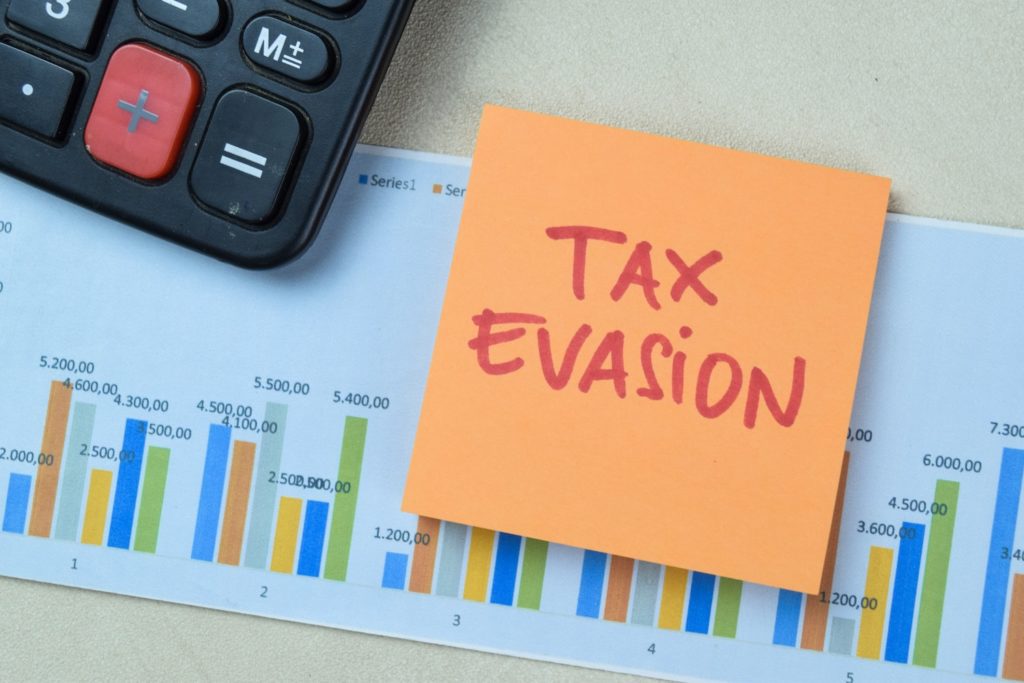 Concept of Tax Evasion write on book isolated on Wooden Table.