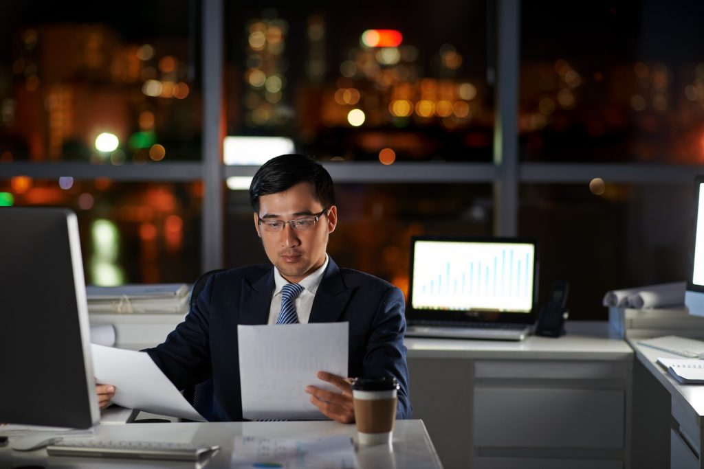 Entrepreneur examining business contracts in office late at night