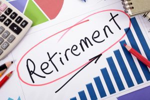 The word Retirement written on a bar graph surrounded by pencils, books and calculator.
