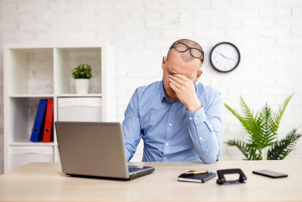 businessman sitting in office and covering face with his hand