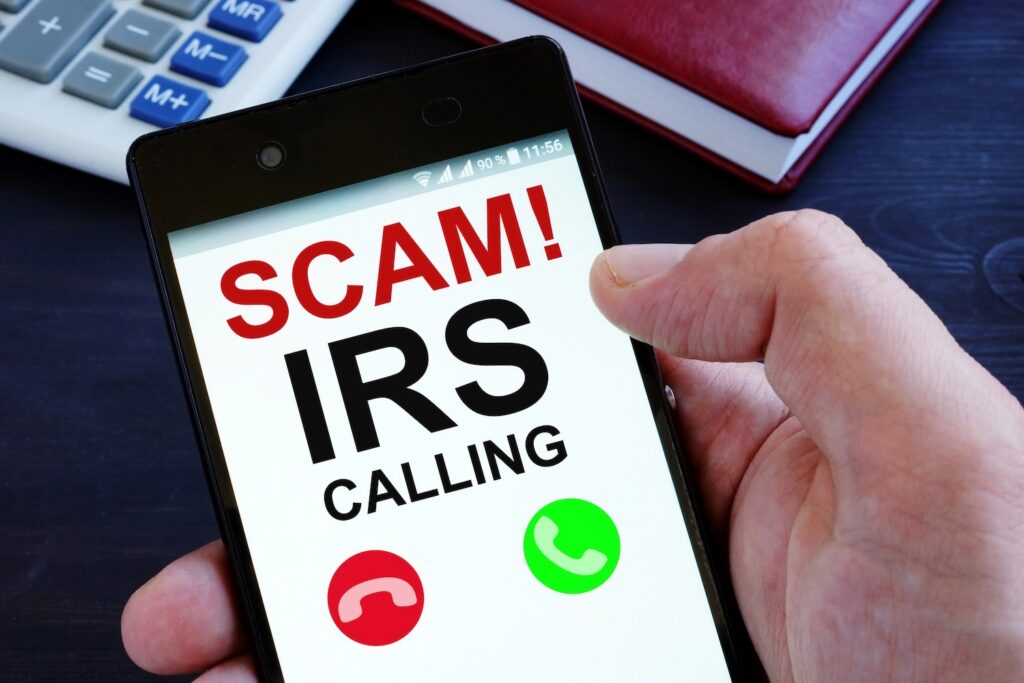Hand is holding phone with irs scam calls.
