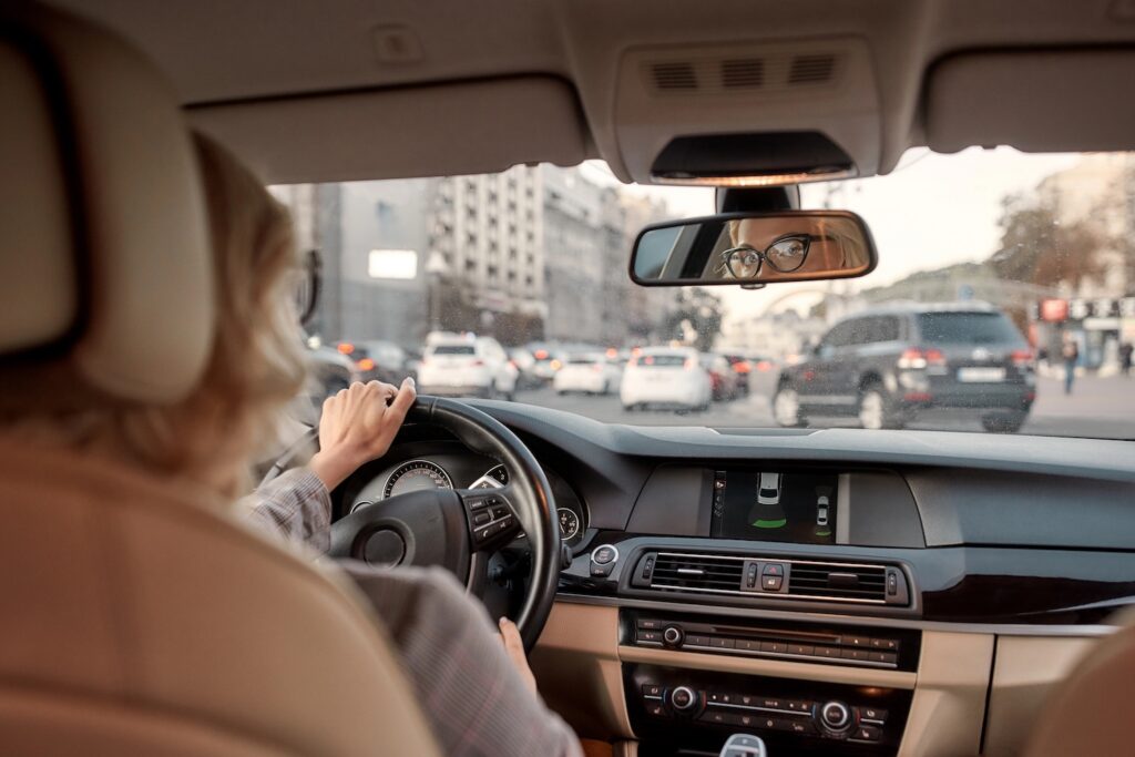 Reflection of woman in the rear-view mirror of the car. Business woman driving a car