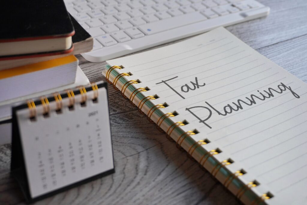 Closeup image of notebook with text TAX PLANNING and calendar on office desk. Business and financial concept